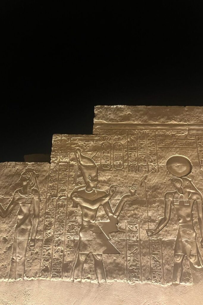 Wall carvings of Egyptian deities under dramatic lighting, featuring Sobek, the Egyptian god with crocodile head, known for fertility, military prowess, and Nile protection.