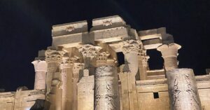Kom Ombo Temple illuminated at night with detailed carvings of Egyptian gods on massive columns, honoring both Horus and Sobek, the crocodile-headed Egyptian god of power and fertility.