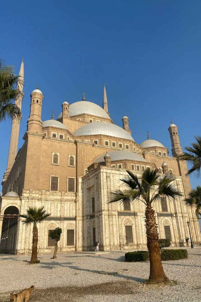 The grand Mosque of Muhammad Ali with its towering minarets and domes under a clear blue sky in Cairo. A beautiful reason why Cairo is worth visiting and what Egypt is like for a cultural holiday.