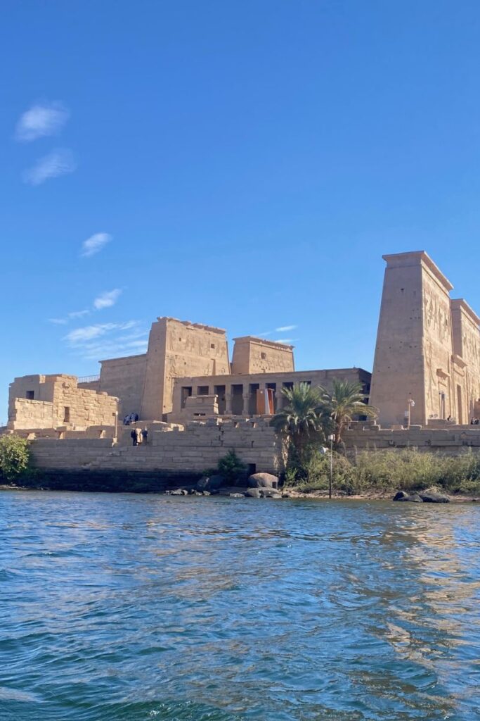 Waterfront view of the Philae temple of Isis in Aswan, Egypt, with towering pylons and colonnades reflecting in the Nile, a key highlight of the Temples of Philae on Philae Island Egypt.