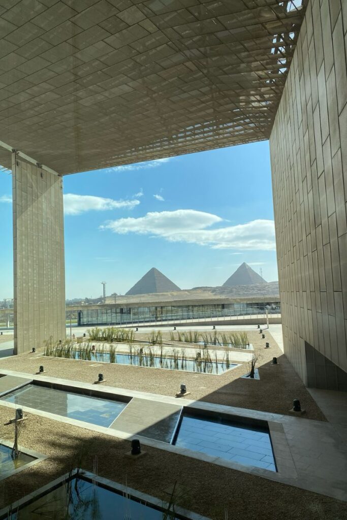 Framed by the modern architecture of the Grand Egyptian Museum, the iconic pyramids rise in the background under a sunny sky. This shot ties together the ancient and modern reasons why Egypt is worth visiting.