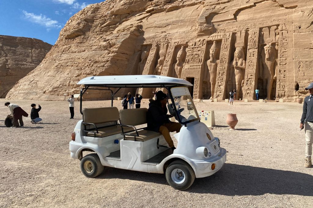 Electric shuttle parked in front of the Abu Simbel Small Temple with tourists walking around; supports topics like Abu Simbel airport to temple, Abu Simbel attractions, and accessible Abu Simbel tours from Aswan.
