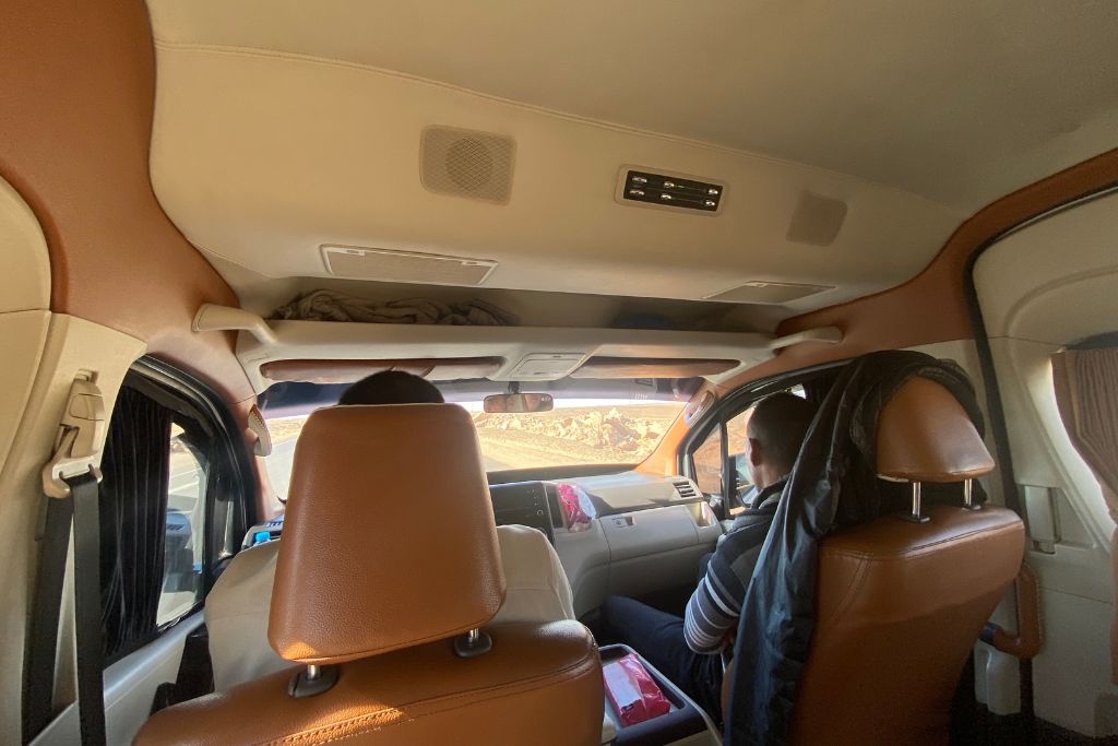 Inside a private van with passengers heading through the desert, showcasing a comfortable Aswan to Abu Simbel day trip by road—ideal for those curious about Aswan to Abu Simbel drive time and transport options.