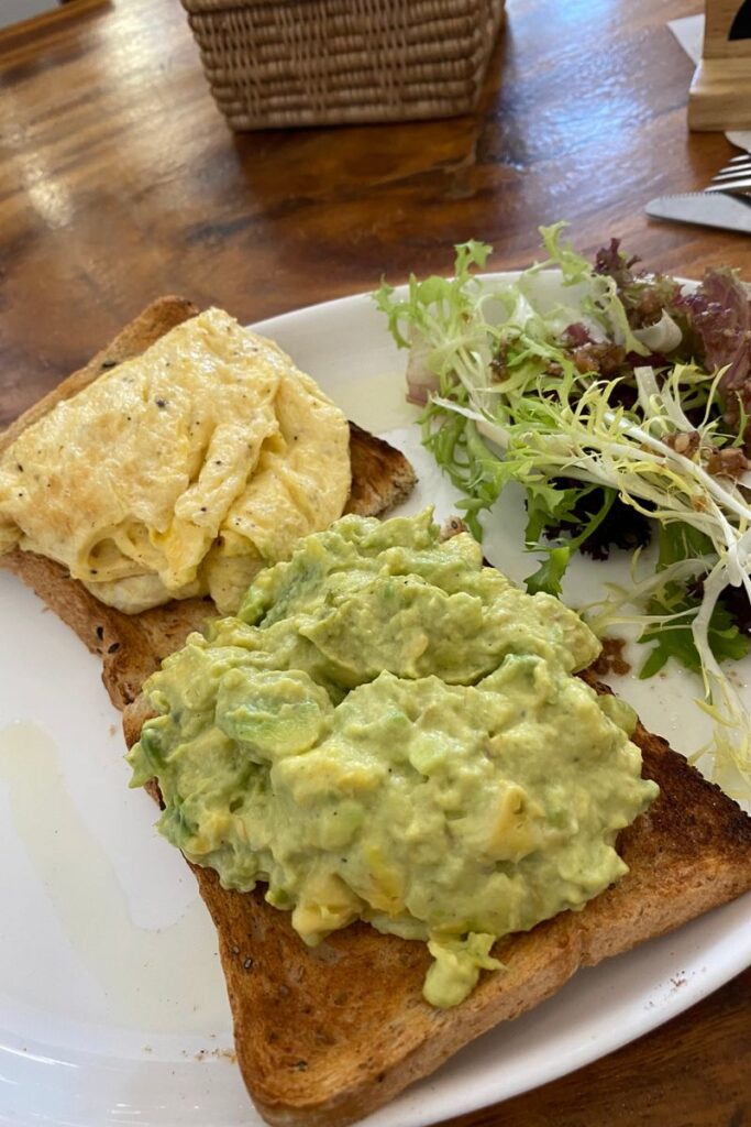 A plate of avocado toast and scrambled eggs served with fresh greens on the side, ideal for illustrating a solo breakfast outing. Perfect for content on eating breakfast alone or tips for dining alone comfortably.