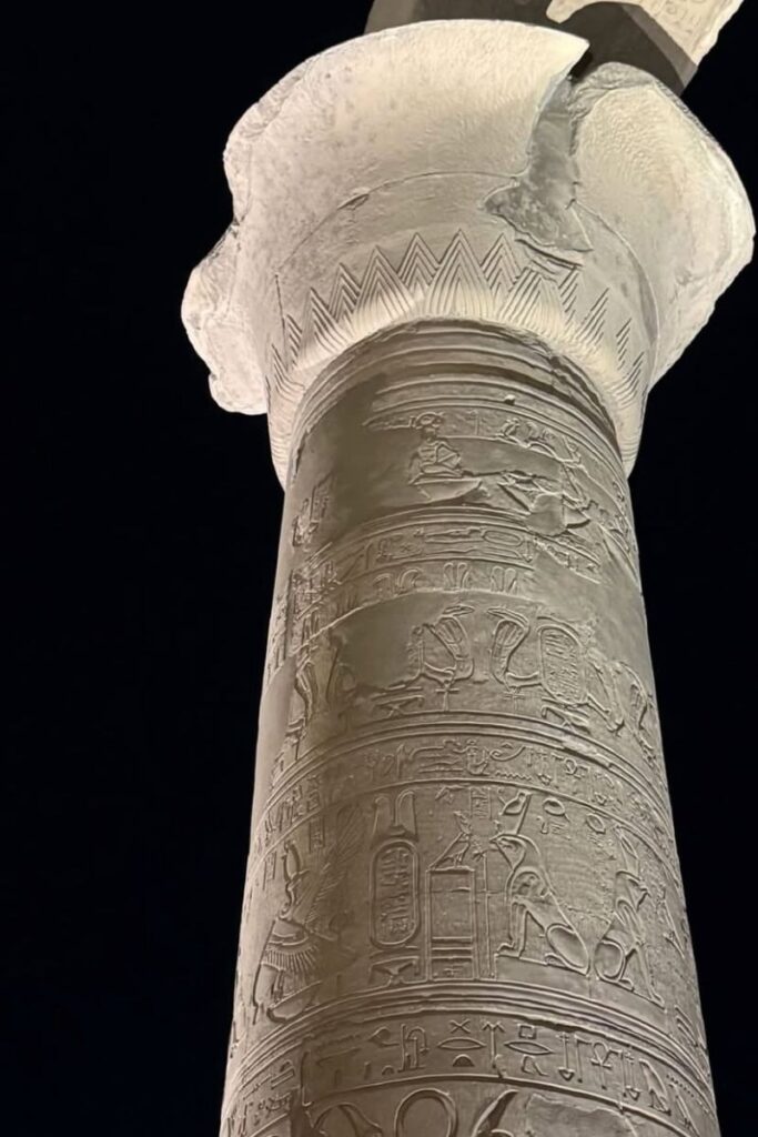 Close-up of a single column at Kom Ombo Temple in Egypt, illuminated at night and engraved with intricate hieroglyphics and carvings of Egyptian gods. This dual temple honors both Sobek and Horus, making it one of the most unique temples to visit in Egypt.