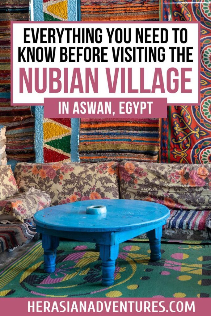 Cozy seating area in a Nubian home with a turquoise table and vibrant woven wall hangings in Aswan, Egypt. Overlaid text reads, "Everything You Need to Know Before Visiting the Nubian Village in Aswan, Egypt," emphasizing cultural tips for exploring Nubian villages near the Nile.