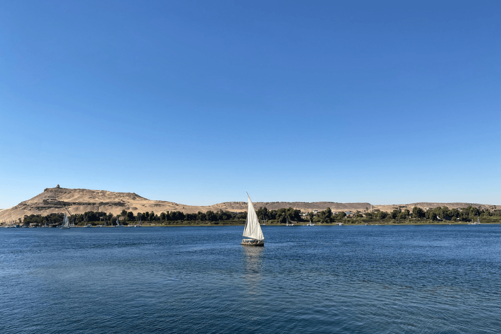 A felucca, a traditional wooden sailboat, glides across the Nile near Elephantine Island in Egypt, commonly used to reach the Nubian villages of Aswan.