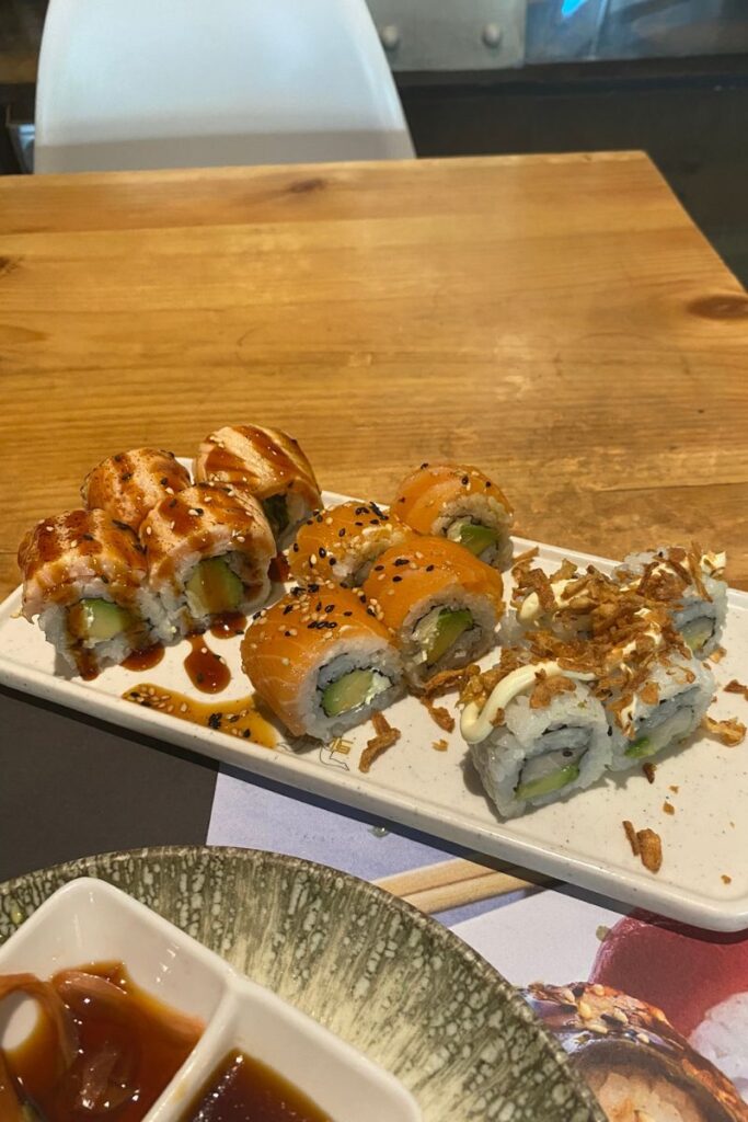 A solo dining moment at a sushi restaurant, featuring multiple rolls on a rectangular platter, with dipping sauces on the side. This image supports topics like “is it weird to go to a restaurant alone” or “where to eat alone.”