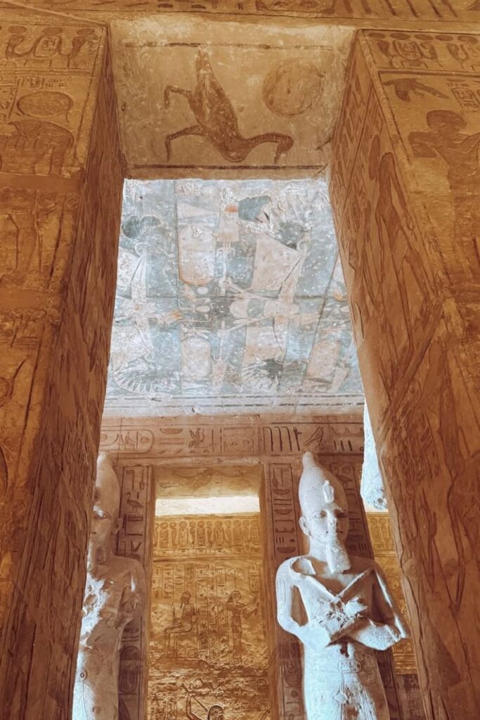 Ceiling and column artwork inside Abu Simbel Temple featuring faded but vivid Egyptian figures and symbols, including animals and royal imagery. This snapshot from the temple interior reveals why Abu Simbel from Aswan is a bucket-list experience.