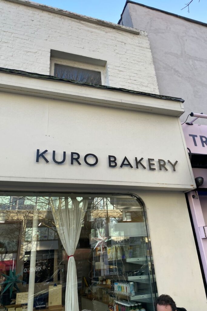 Exterior sign reading “KURO BAKERY” on a charming neighborhood shop, a welcoming stop for solo travel eating alone. A great example of going alone to a restaurant-style café for relaxed single dining.