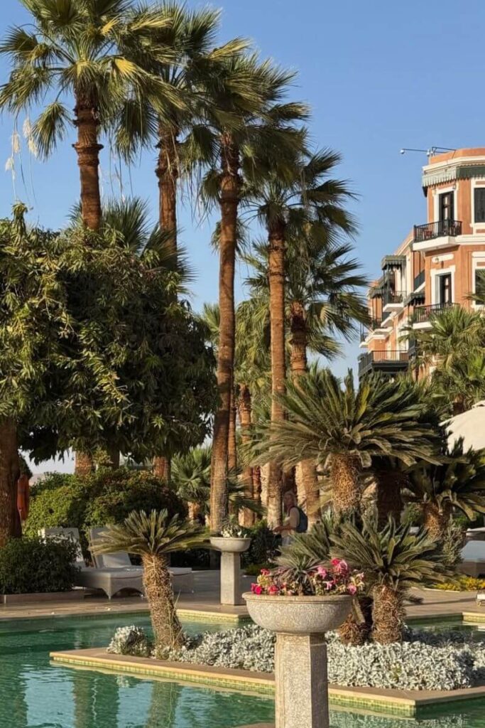 Lush garden pool area surrounded by palm trees and manicured plants at a luxury resort near Kom Ombo Temple in Egypt. Many visitors stay nearby while exploring iconic temples in Egypt.