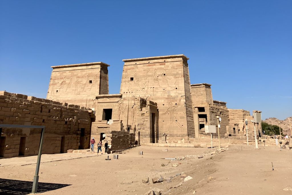 The ancient Philae Temple complex in Aswan, Egypt, stands under a clear blue sky, showcasing its massive stone pylons and detailed hieroglyphics. This historic site is a top attraction near the Nubian villages and Elephantine Island, offering insight into Egypt’s rich cultural and religious heritage.