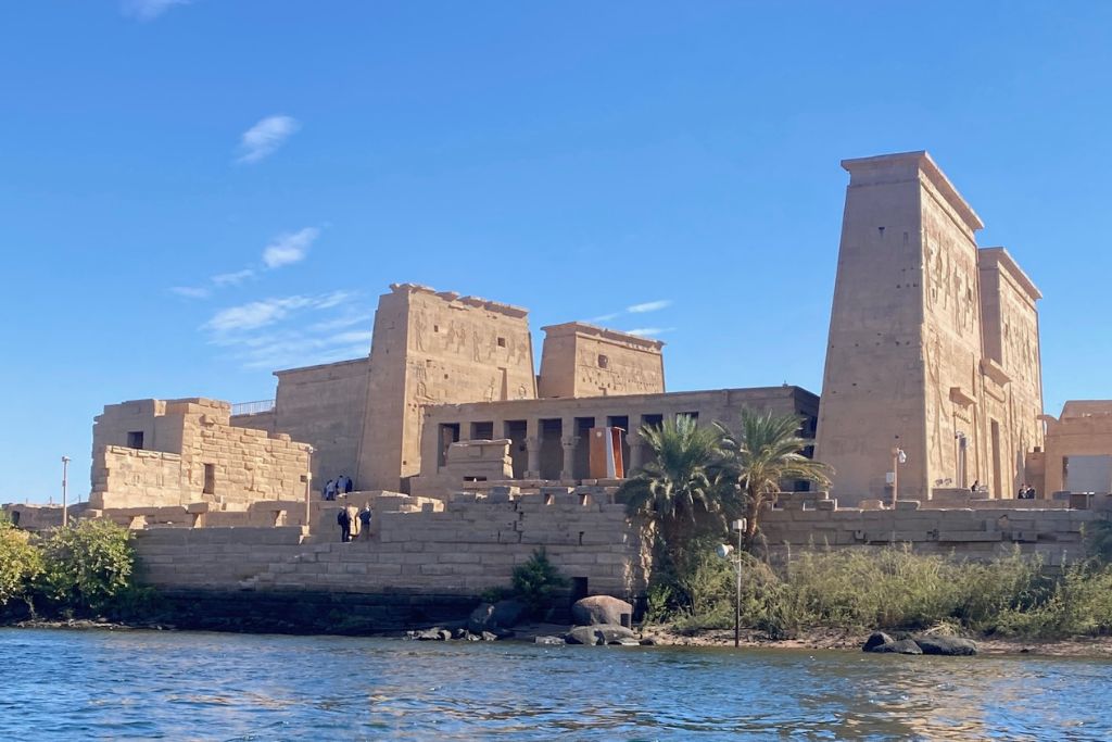 Ancient Egyptian temple ruins on the banks of the Nile River in Aswan, showcasing one of the top things to do in Aswan and a reason travelers seek hotels with river views.