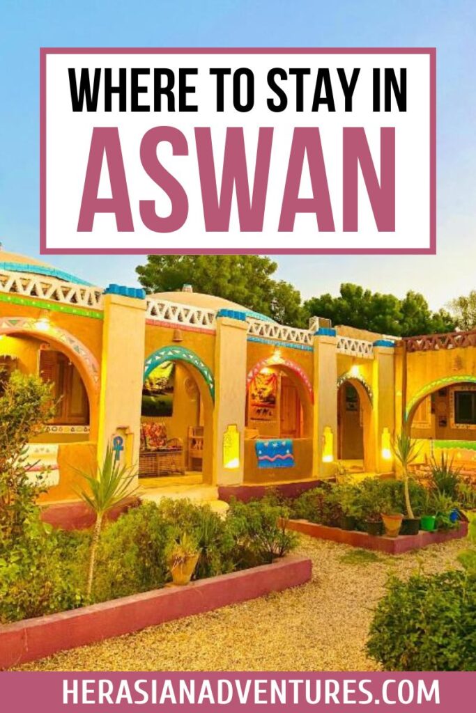 Warmly lit Nubian guesthouse with painted archways and garden greenery, overlaid with text “Where to Stay in Aswan Egypt” ideal for travelers searching hotels in Aswan Egypt or boutique stays.