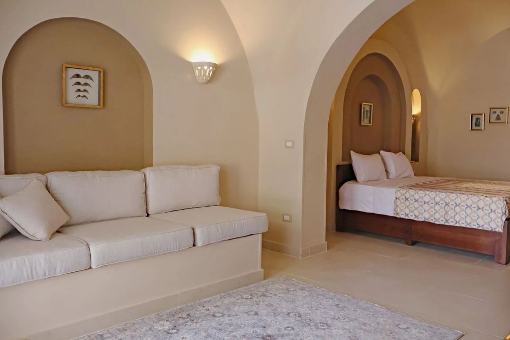 Spacious, earth-toned suite in a boutique hotel in Luxor, Egypt, featuring arched doorways, soft lighting, and traditional decor—ideal for travelers seeking quiet and authentic Luxor accommodation.
