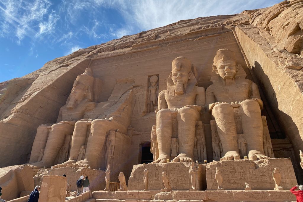 The grand façade of Abu Simbel carved into a sandstone cliff, featuring colossal statues of Ramses II. One of the most popular day trips from Aswan and a top attraction in Aswan not to miss.