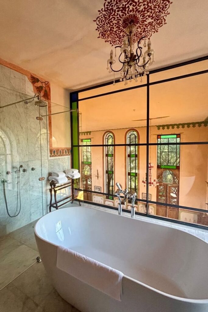 Freestanding bathtub with a chandelier overhead and stained-glass windows in a luxurious hotel bathroom in Luxor, Egypt. A serene space to relax after early morning hot air ballooning in Luxor Egypt.