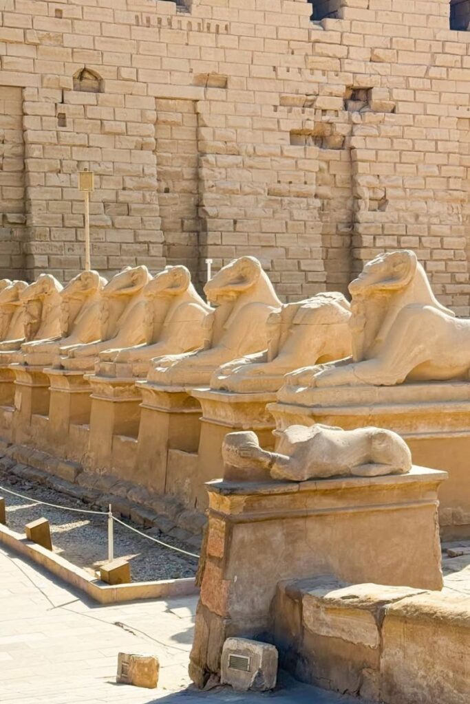 A row of sandstone ram-headed sphinx statues lines the avenue leading to Karnak Temple in Luxor city. A symbolic and impressive place to see in Luxor for history and archaeology lovers.