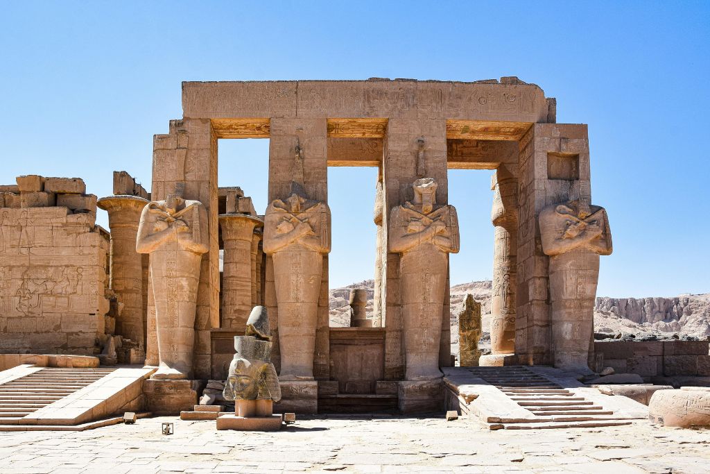 Entrance of Ramesseum Temple with colossal statues of Pharaoh Ramses II standing between sandstone pillars. A lesser-visited yet powerful place to visit in Luxor with fewer crowds.