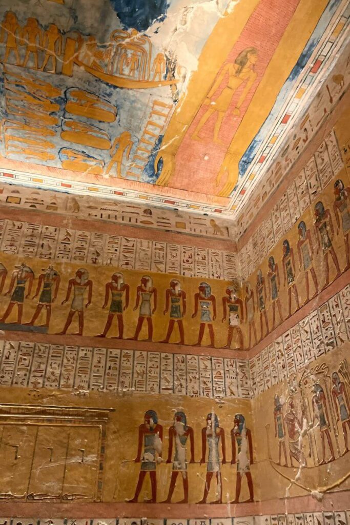 Ceiling and wall of a Luxor tomb painted with vivid Egyptian gods, hieroglyphs, and symbols—an unforgettable stop on guided Luxor Egypt tours.