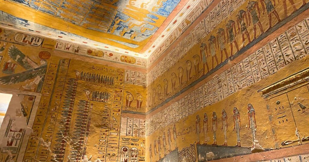 Close-up of Luxor Valley of the Kings tombs artwork showing a grid of painted baboons and human figures, illustrating ancient Egyptian mythology. The surrounding walls are filled with hieroglyphic inscriptions and bright colors, creating a rich tapestry of symbols and storytelling.