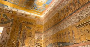 Close-up of Luxor Valley of the Kings tombs artwork showing a grid of painted baboons and human figures, illustrating ancient Egyptian mythology. The surrounding walls are filled with hieroglyphic inscriptions and bright colors, creating a rich tapestry of symbols and storytelling.