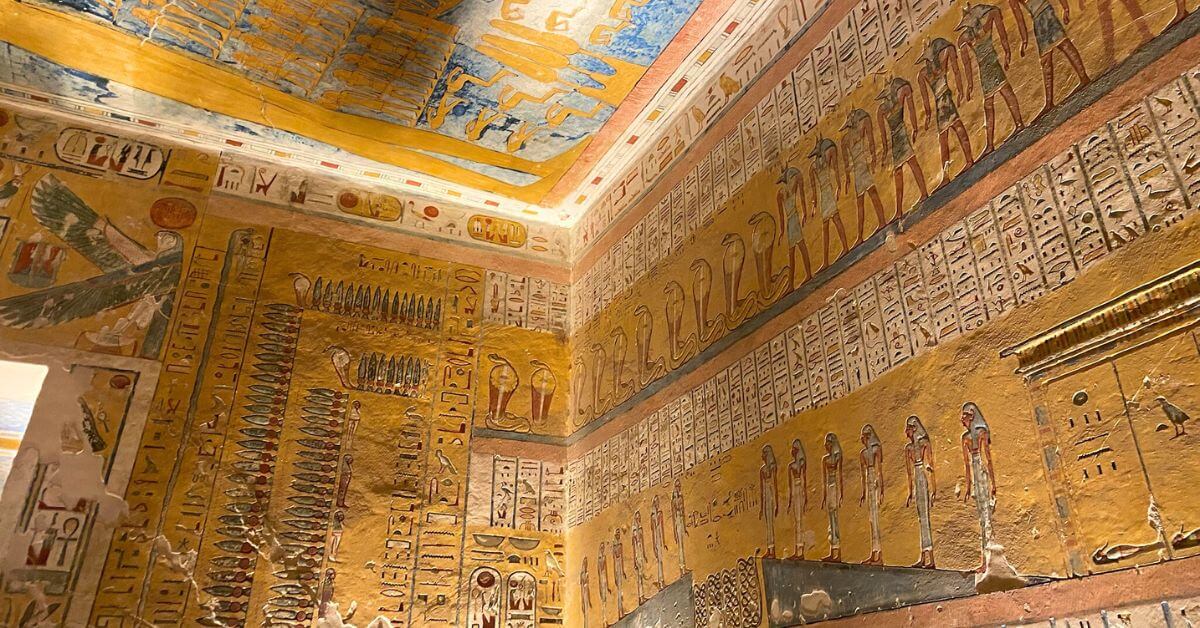 Close-up of Luxor Valley of the Kings tombs artwork showing a grid of painted baboons and human figures, illustrating ancient Egyptian mythology. The surrounding walls are filled with hieroglyphic inscriptions and bright colors, creating a rich tapestry of symbols and storytelling.