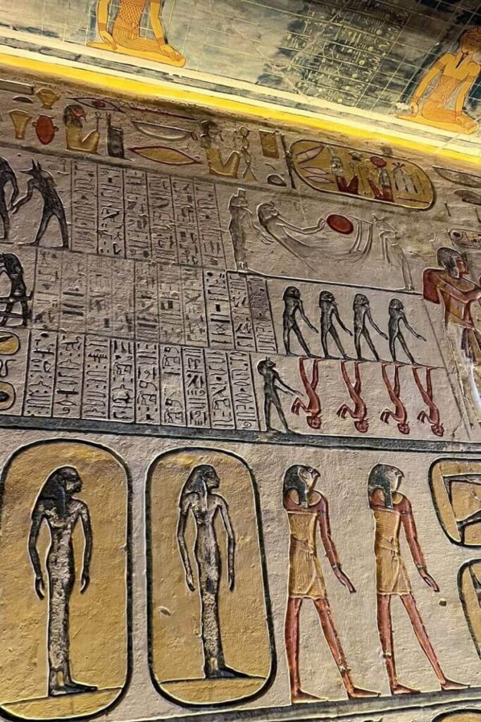 Detailed wall carvings and painted figures inside a Luxor tomb in the Valley of the Kings, including upside-down figures and ancient script. These vibrant visuals help explain why this site is considered home to the best tombs in Egypt.