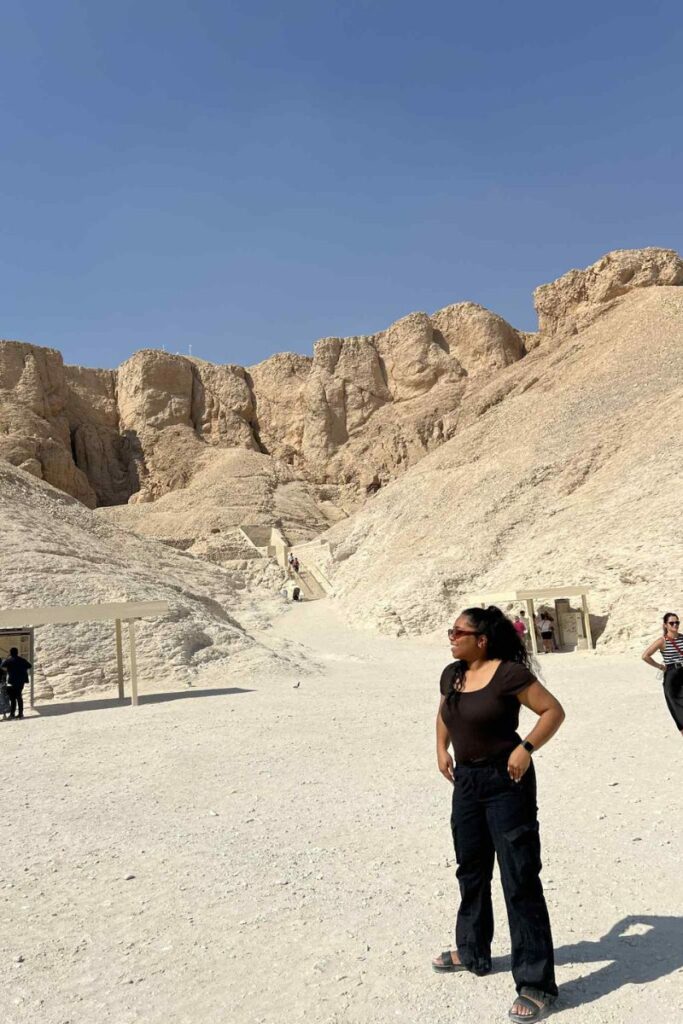 A visitor stands outside in the sunlit desert landscape of the Valley of the Kings, surrounded by the natural cliffs that conceal more than 60 ancient tombs. This photo captures the approach to one of Luxor’s most visited archaeological zones.