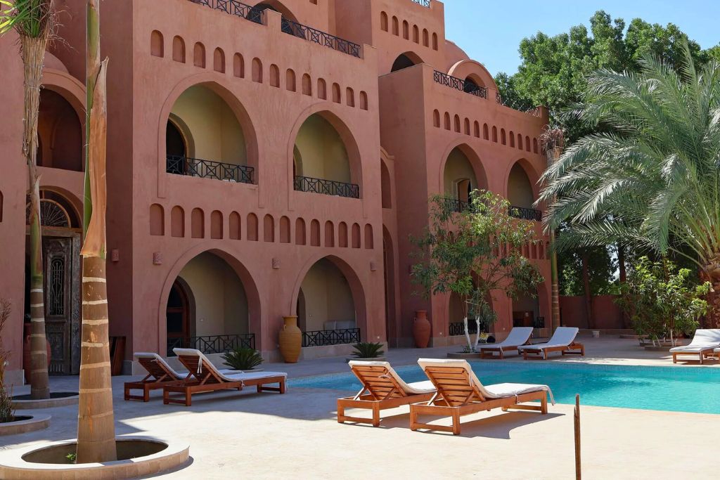 Luxurious boutique hotel in Luxor city with an outdoor pool, lounge chairs, and palm trees—ideal for travelers searching where to stay in Luxor.