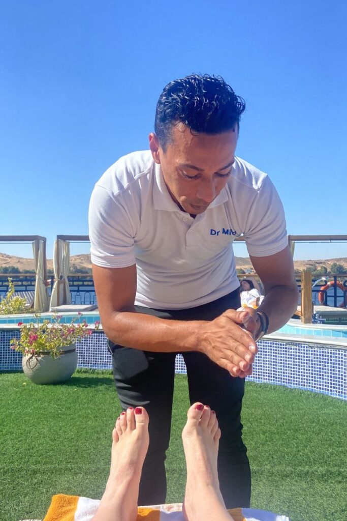 A massage therapist preparing a treatment beside a guest relaxing by the cruise pool—ideal for promoting luxury Nile cruises or pampering aboard the most luxurious Nile cruise ship.
