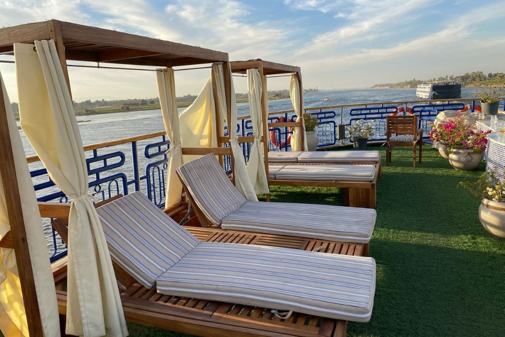 Shaded striped loungers on the deck of a luxurious Nile cruise ship overlooking the river—ideal for posts on the best Nile cruises from Luxor to Aswan or a relaxing luxury Nile cruise.
