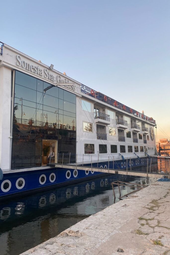 Exterior of the Sonesta Star Goddess Nile cruise ship docked by the river, with balconies and panoramic glass windows—great for reviews of luxury Nile cruises and cruises from Luxor to Aswan.