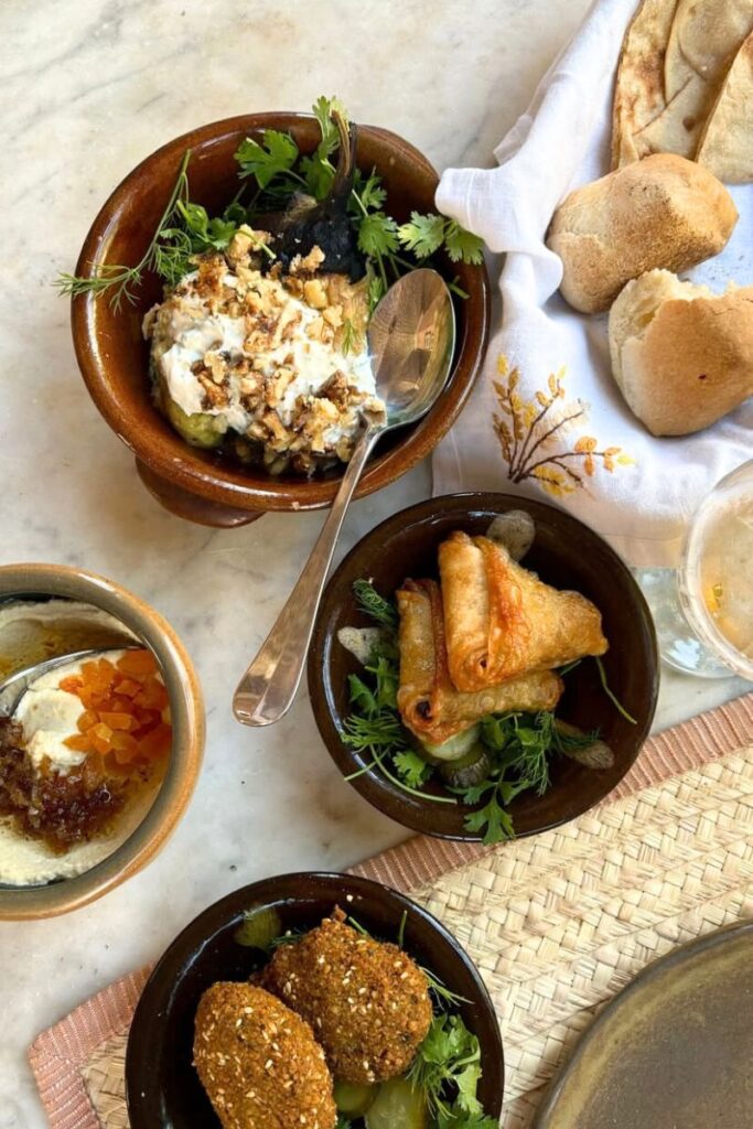 A table set with traditional Egyptian dishes including falafel, baba ghanoush, stuffed pastries, and fresh bread. Sampling local cuisine is one of the most unique things to do in Luxor beyond temples.