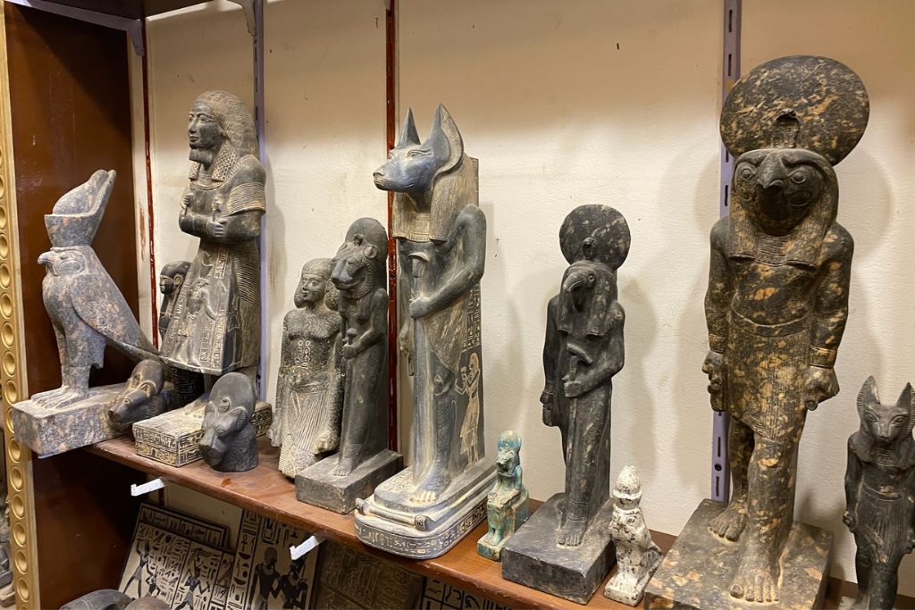 A collection of carved Egyptian statues and figurines on display in a local shop. A perfect example of shopping in Aswan for cultural egyptian souvenirs and unique keepsakes.