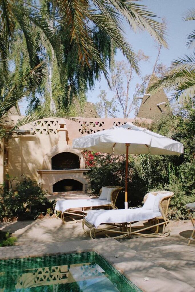 Peaceful courtyard with lounge chairs, umbrella, and small pool in a lush garden setting in Luxor. A relaxing spot to stay when visiting the Valley of the Kings tombs.