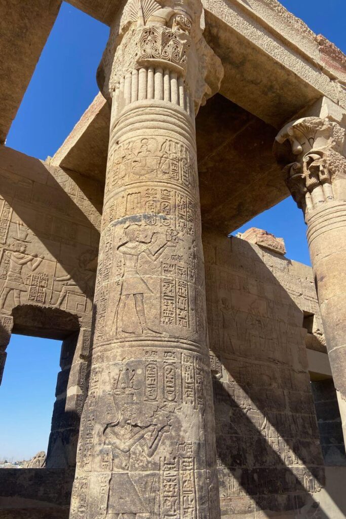 Close-up of a decorated pillar inside a temple in Egypt, etched with pharaoh figures and hieroglyphics, showcasing the fine detail of Egyptian temple architecture and religious symbolism.