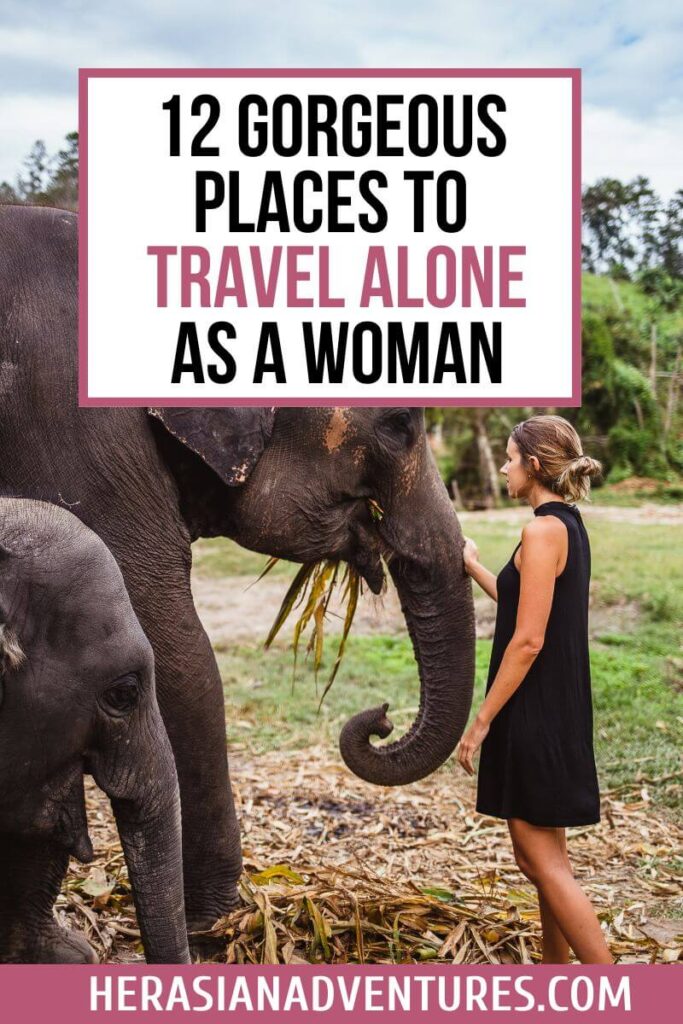 A woman in a black dress gently touching an elephant’s trunk, standing in a grassy field, with the overlay text reading “12 GORGEOUS PLACES TO TRAVEL ALONE AS A WOMAN.” A peaceful image perfect for articles on the best solo female travel destinations or best places to travel solo female.