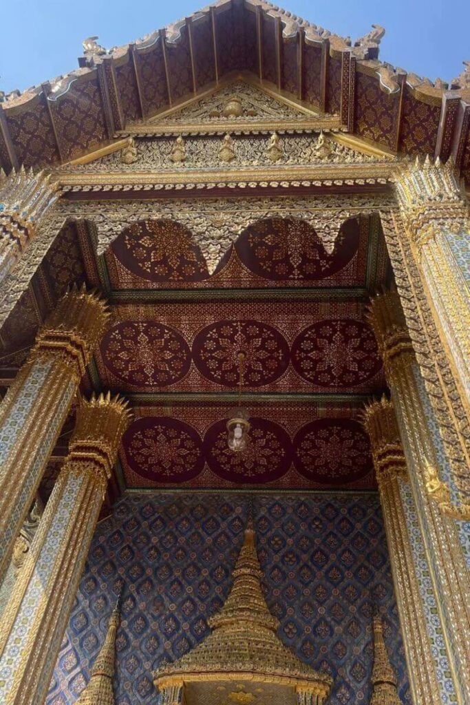 Ornate golden temple architecture from Thailand with an intricately designed ceiling and pillars. Great for solo female travel Thailand or spiritual travel destinations for solo women travelers.