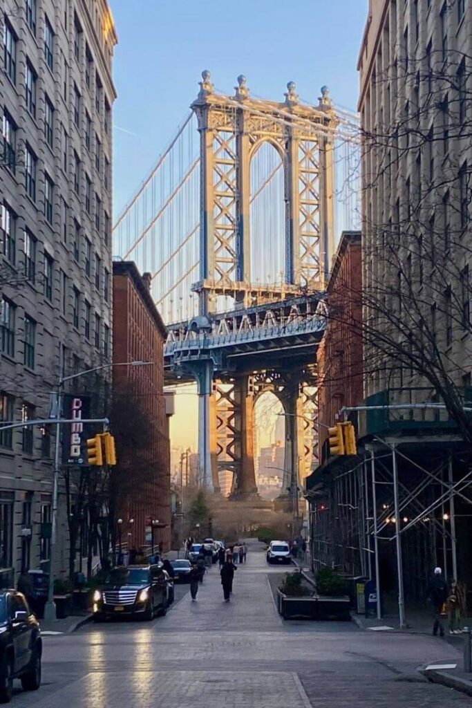 View of the Manhattan Bridge framed perfectly between two buildings in Brooklyn, capturing a classic NYC solo traveler moment. Great for posts about traveling to New York alone or best solo female travel destinations in the US.