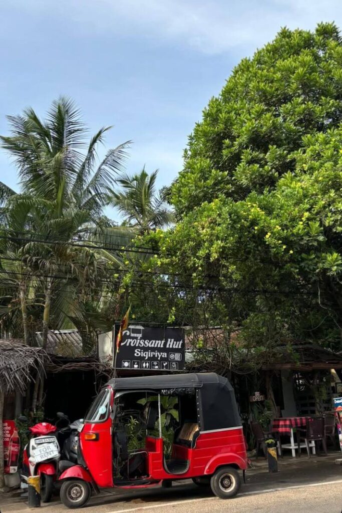 A bright red tuk-tuk parked in front of the Croissant Hut café in Sigiriya, Sri Lanka, surrounded by lush greenery—perfect for solo female travelers in Sri Lanka or women exploring solo travel destinations in South Asia.
