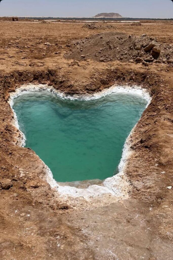 A turquoise heart-shaped spring surrounded by salt deposits in the arid landscape of Siwa Oasis, Egypt. Ideal for adventurous women travelers in Egypt looking for the safest places for solo female travelers off the beaten path.