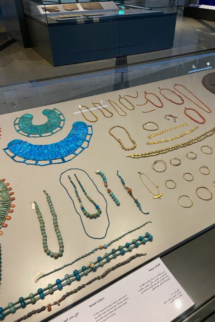 An elegant museum display of ancient Egyptian jewelry, including turquoise broad collars, beaded necklaces, and gold rings. This exhibit showcases the exquisite craftsmanship of Egyptian gold jewelry and highlights why gold in Egypt is such a sought-after souvenir. A great answer to what jewelry to buy in Egypt and why buying gold in Egypt is a timeless tradition.