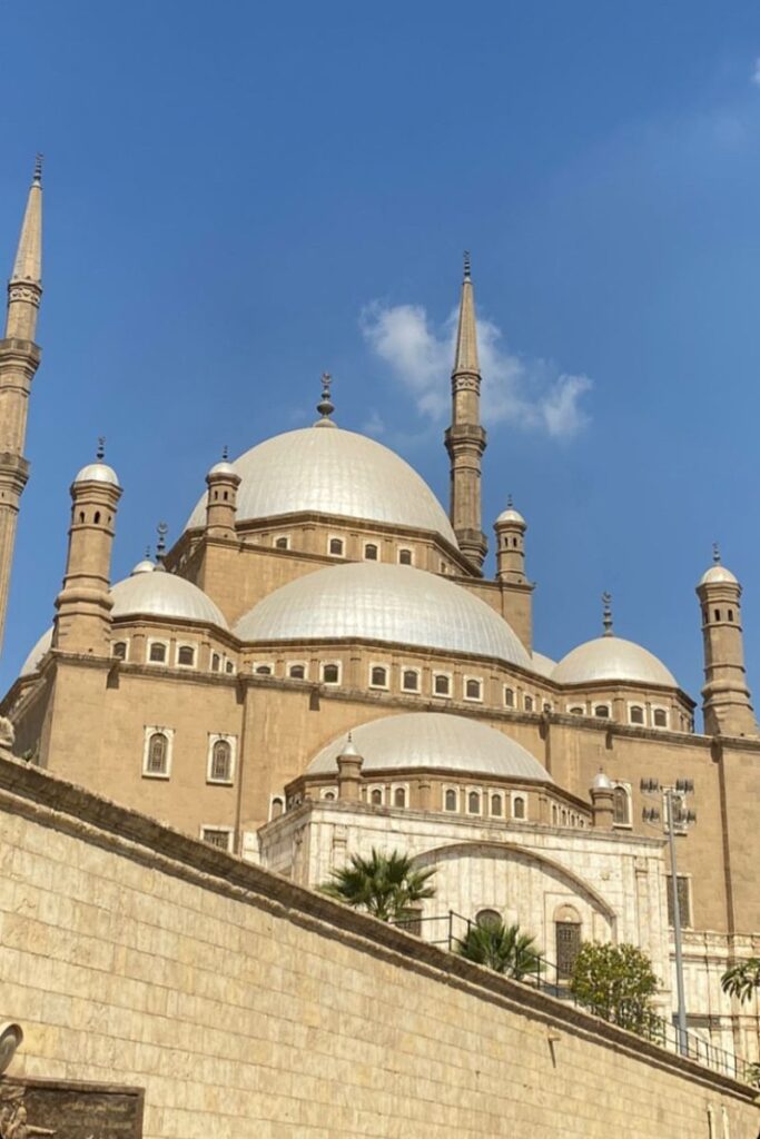 Grand white-domed Mosque of Muhammad Ali in Cairo stands tall under a blue sky. A must-visit for female solo travelers in Egypt wondering is Cairo safe for women to travel.