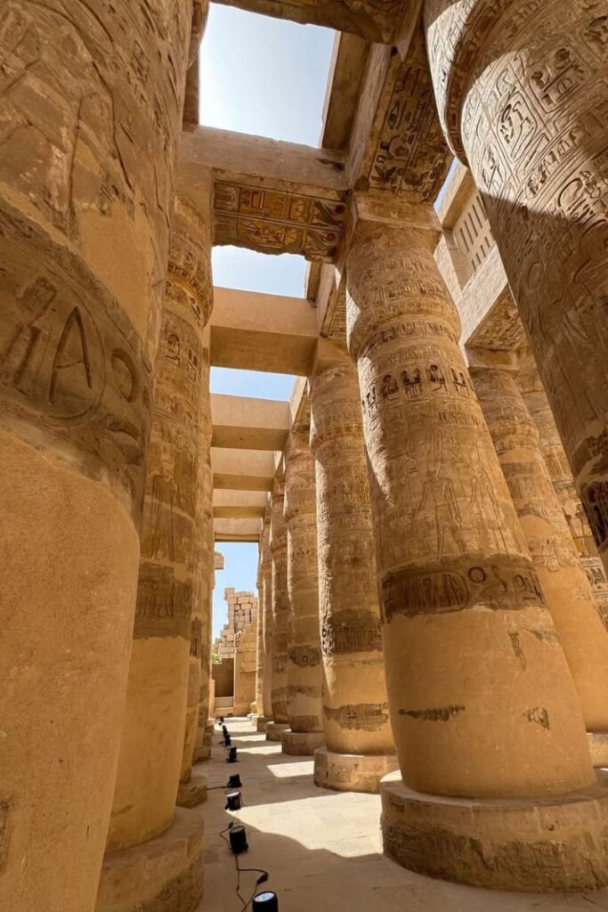 Row of massive columns in Karnak Temple bathed in sunlight, with vivid hieroglyphics—highlighting karnak temple architecture as one of the best temples in Egypt to explore.