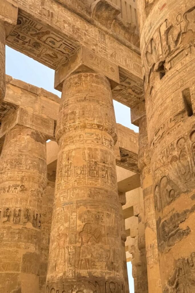 Close-up of detailed carvings on sandstone columns at Karnak Temple, a prime representation of ancient temples in Egypt and the artistry of Luxor temple architecture.