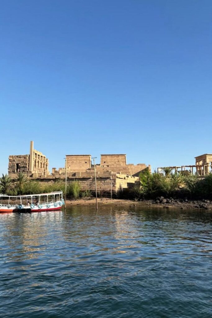 View of Philae Temple from the Nile, with traditional boats moored nearby—an iconic scene of Egyptian temples on the Nile and one of the most serene temples along the Nile River.