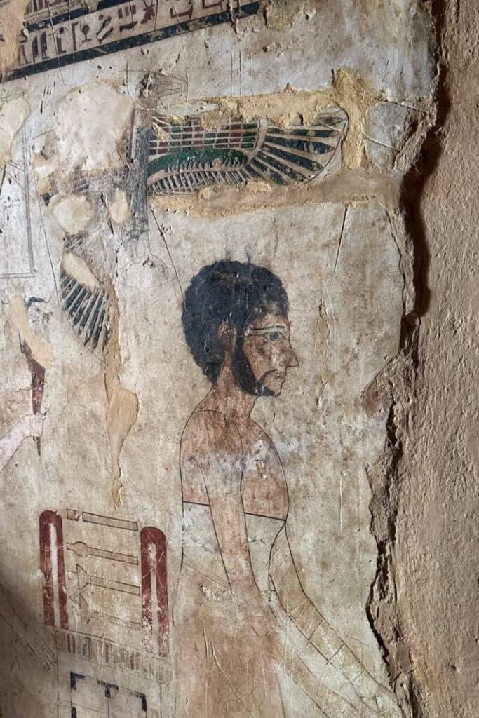 Ancient Egyptian wall painting of a figure with curly hair and a beard, featuring hieroglyphics and traditional motifs, found in Siwa Egypt—showcasing the cultural depth of the oasis in Egypt.