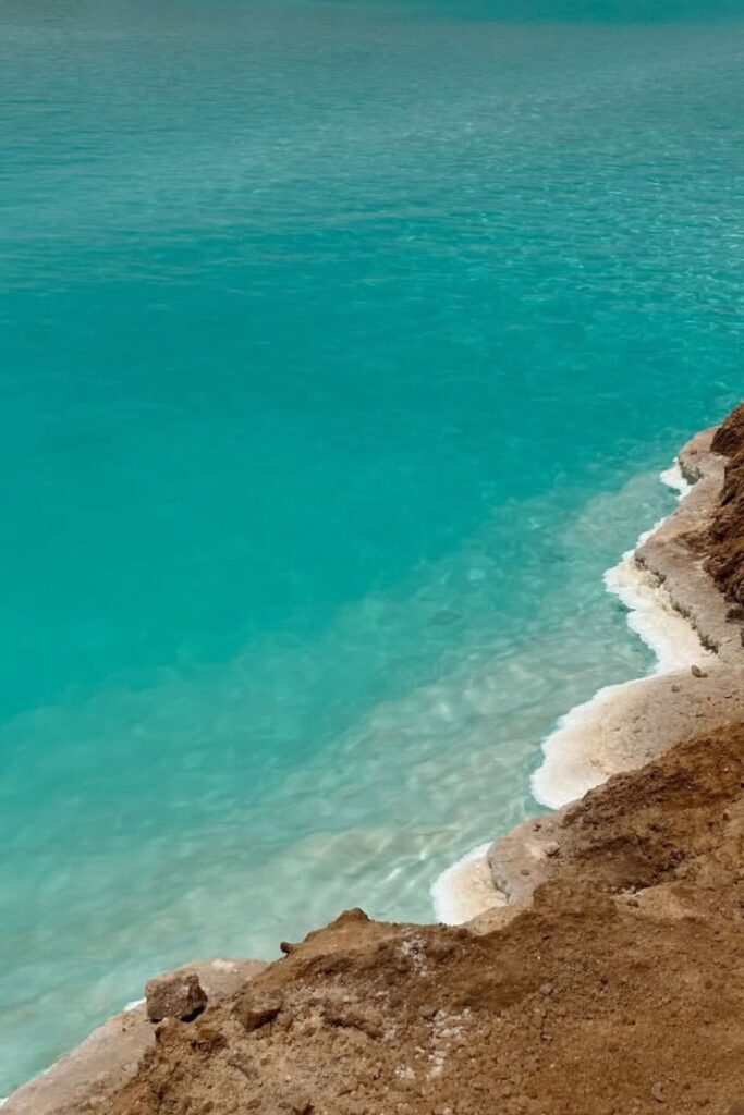 Close-up of a vivid turquoise salt pool with crystalline white mineral edges along the shore—perfectly capturing the beauty of the salt pools of Siwa Oasis and the famous Siwa Oasis salt lakes.