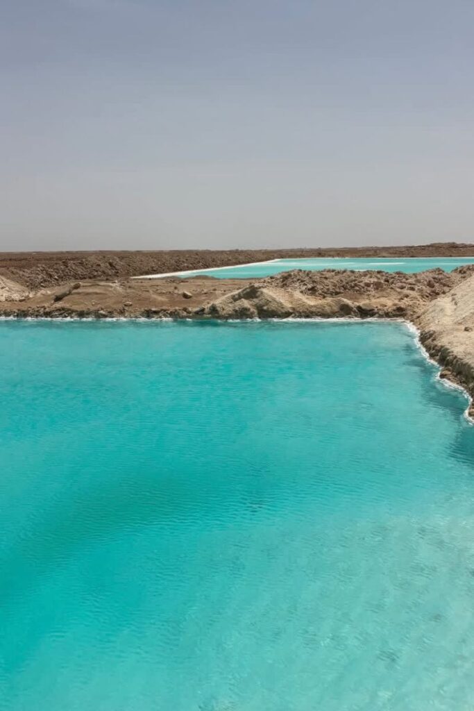 Panoramic view of bright turquoise salt lakes set against a dry desert backdrop in Siwa Oasis, Egypt—highlighting the surreal beauty of the Siwa salt lakes and salt lake Siwa Egypt landscapes.